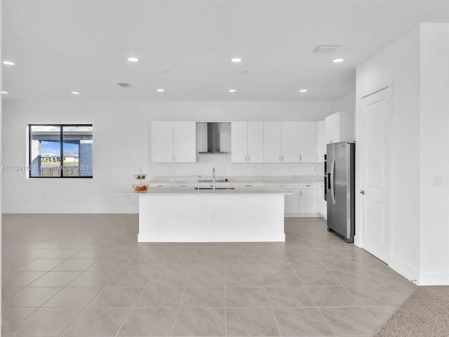 kitchen featuring stainless steel fridge with ice dispenser, an island with sink, wall chimney exhaust hood, white cabinets, and sink