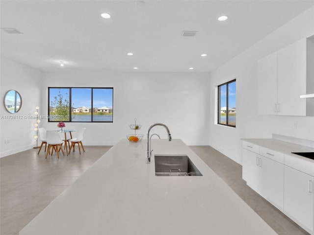 kitchen featuring sink, white cabinetry, light tile patterned floors, and black electric cooktop