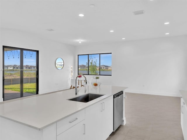 kitchen with stainless steel dishwasher, a healthy amount of sunlight, sink, and white cabinetry