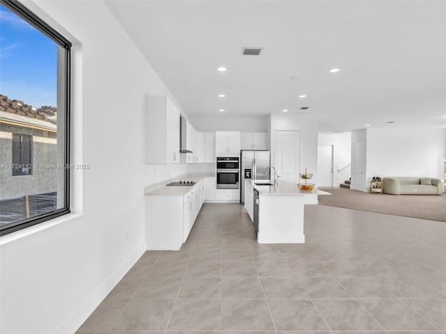 kitchen with white cabinets, a kitchen island with sink, light tile patterned flooring, and black electric stovetop