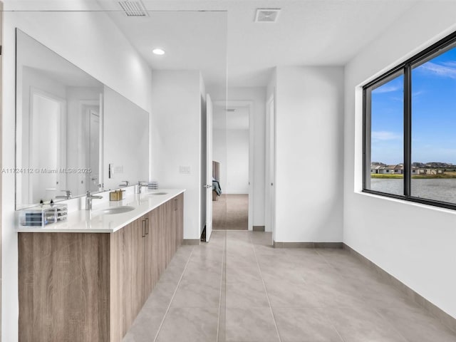 bathroom with tile patterned flooring, a water view, and vanity