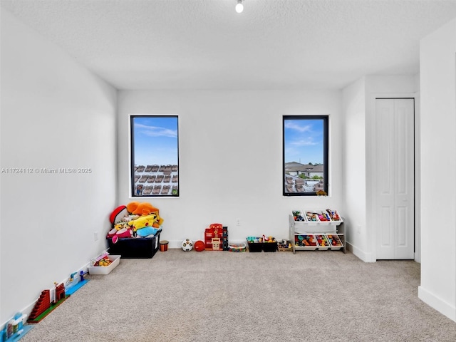 recreation room featuring a textured ceiling and carpet flooring