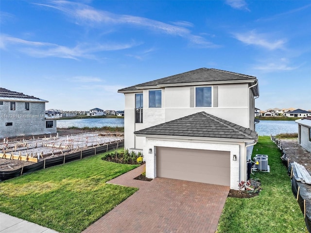 view of front of house with a garage, a front lawn, a water view, and central air condition unit