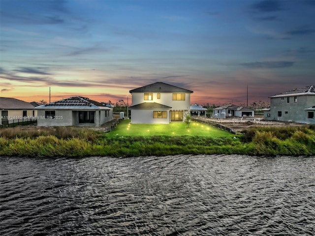 back house at dusk featuring a water view