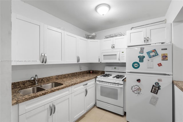 kitchen featuring white cabinetry, sink, dark stone countertops, white appliances, and light tile patterned flooring