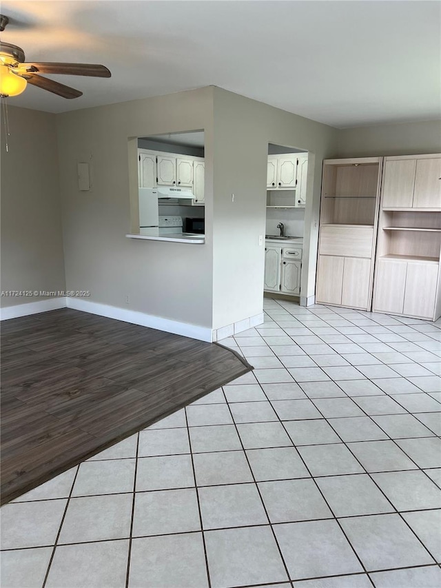 unfurnished living room with ceiling fan, light tile patterned flooring, and sink