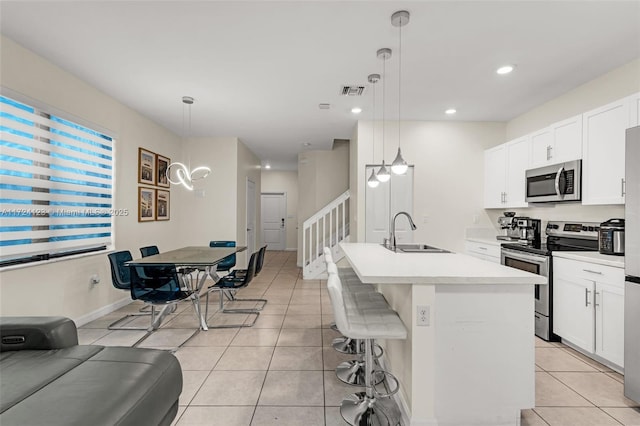 kitchen with sink, decorative light fixtures, an island with sink, and appliances with stainless steel finishes