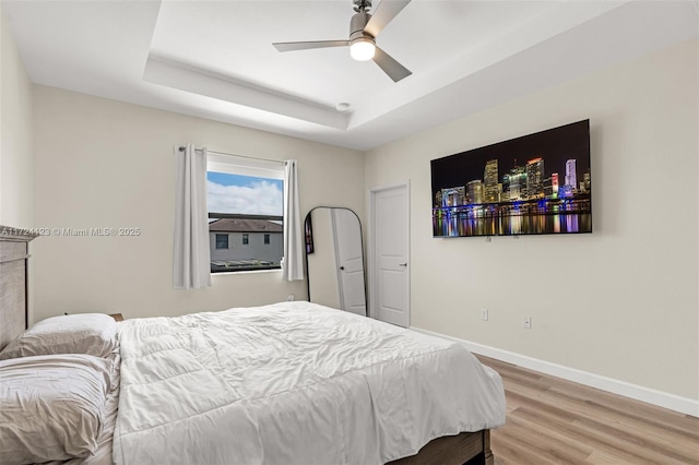 bedroom featuring hardwood / wood-style flooring, a raised ceiling, and ceiling fan