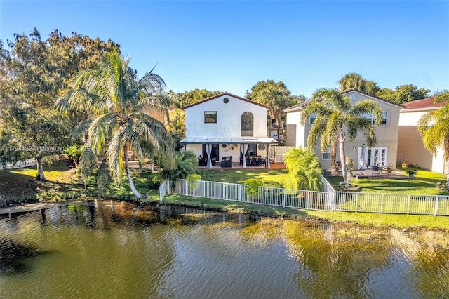 rear view of house with a patio area, a yard, and a water view