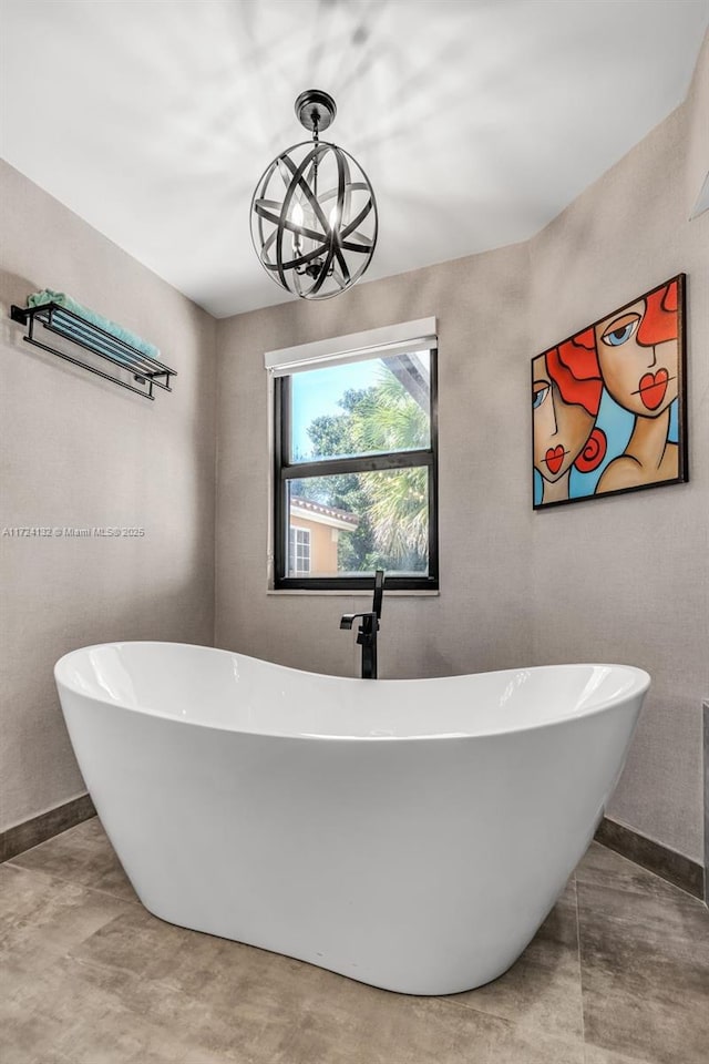 bathroom with a tub to relax in and a notable chandelier