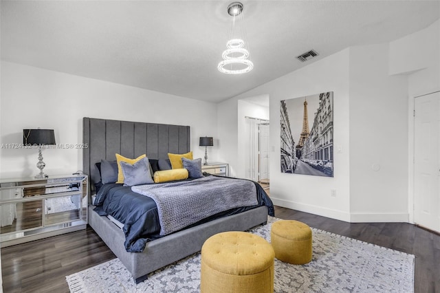 bedroom featuring dark hardwood / wood-style flooring, vaulted ceiling, and a notable chandelier