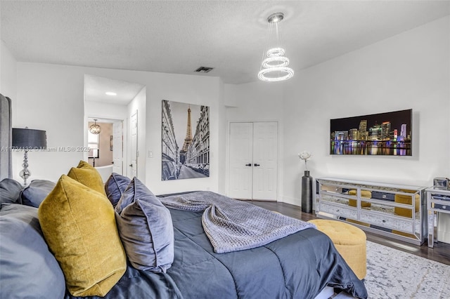 bedroom featuring dark hardwood / wood-style floors, a textured ceiling, and a chandelier