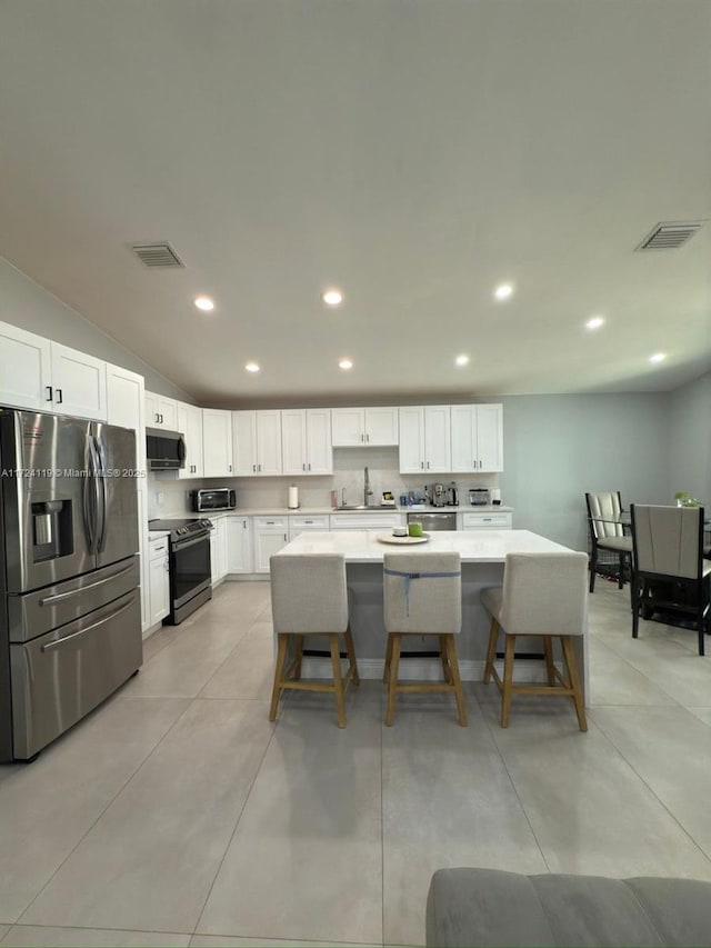 kitchen featuring white cabinetry, a center island, sink, a kitchen bar, and appliances with stainless steel finishes