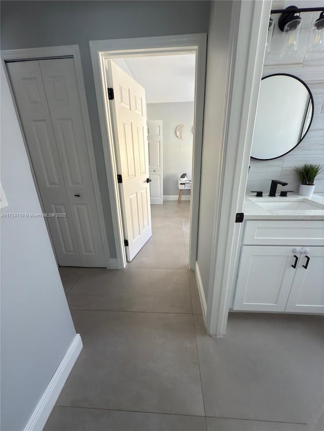 hallway featuring sink and light tile patterned flooring