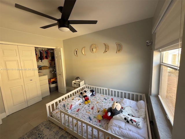 bedroom with ceiling fan, dark tile patterned floors, and a closet