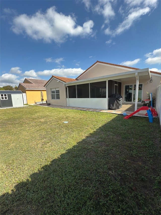 rear view of property featuring a sunroom, a storage shed, and a yard