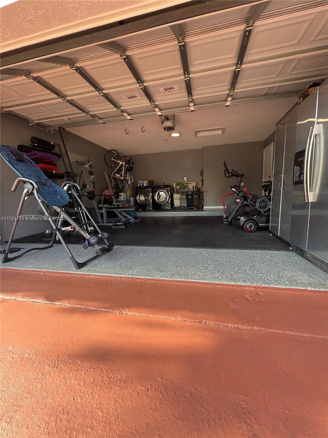 garage featuring stainless steel fridge with ice dispenser, separate washer and dryer, and a garage door opener