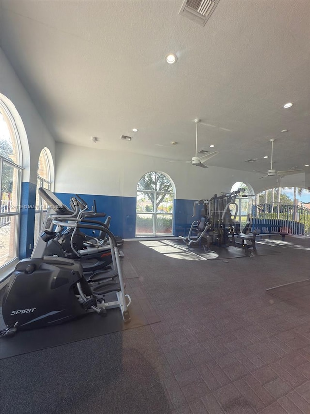 gym featuring ceiling fan and a textured ceiling