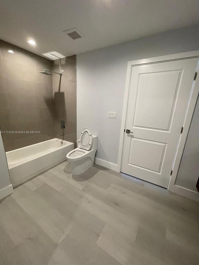 bathroom with tiled shower / bath combo and toilet