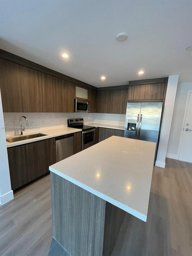 kitchen featuring light stone counters, sink, stainless steel appliances, and light hardwood / wood-style floors