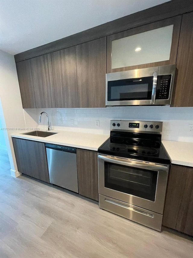 kitchen featuring backsplash, stainless steel appliances, light hardwood / wood-style floors, and sink