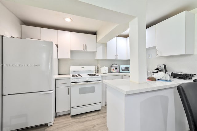 kitchen with light wood-type flooring, white appliances, kitchen peninsula, and white cabinetry