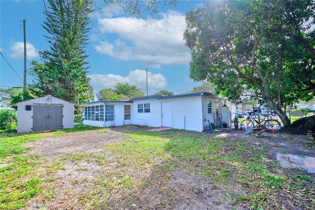 back of property with a storage shed, a sunroom, stucco siding, and an outdoor structure