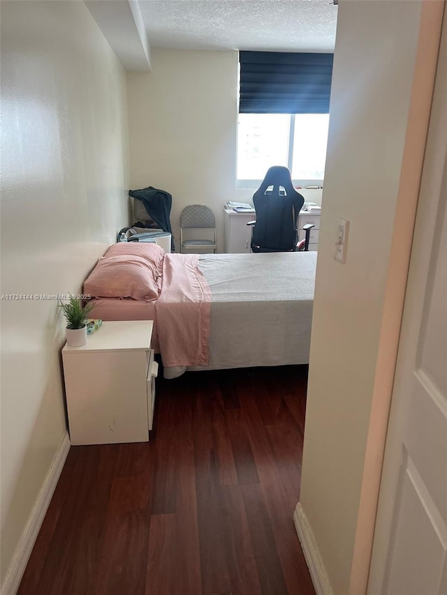 bedroom with a textured ceiling and dark wood-type flooring