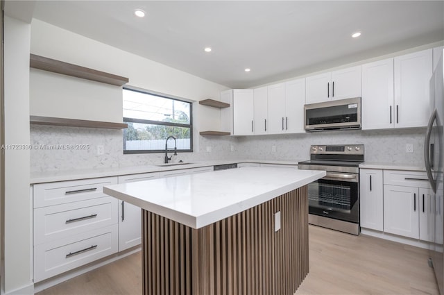 kitchen with appliances with stainless steel finishes, a center island, white cabinetry, and sink