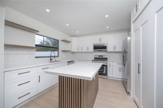 kitchen with a center island, sink, stainless steel appliances, light hardwood / wood-style flooring, and white cabinets