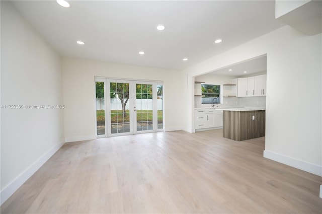 unfurnished living room featuring french doors, light hardwood / wood-style floors, and sink