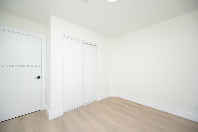 unfurnished bedroom with a closet and light wood-type flooring