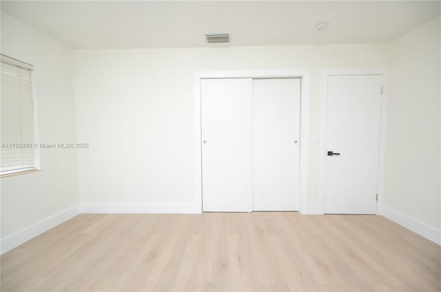 unfurnished bedroom featuring light hardwood / wood-style floors and a closet