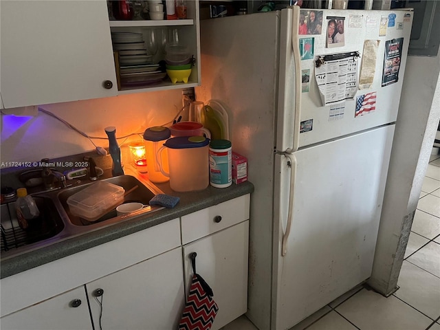 kitchen featuring white cabinets, light tile patterned floors, white refrigerator, and sink