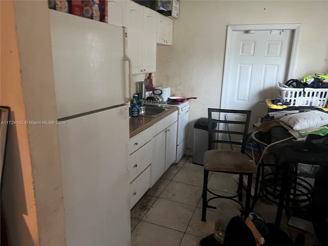 kitchen with sink, white cabinets, light tile patterned floors, and white refrigerator