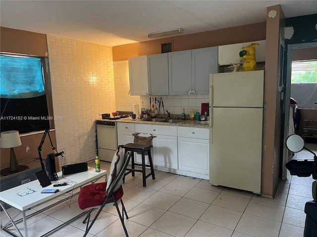 kitchen featuring white cabinetry, sink, white appliances, decorative backsplash, and light tile patterned flooring