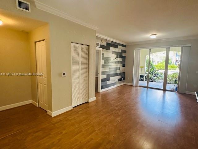 unfurnished living room featuring dark hardwood / wood-style floors and crown molding