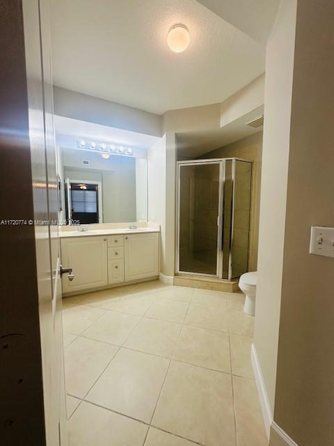 bathroom with tile patterned floors, a textured ceiling, vanity, a shower with door, and toilet