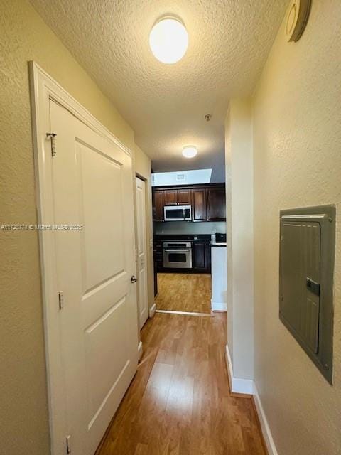 hallway with light hardwood / wood-style flooring and a textured ceiling