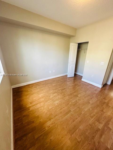 unfurnished bedroom with hardwood / wood-style flooring, a textured ceiling, and a closet