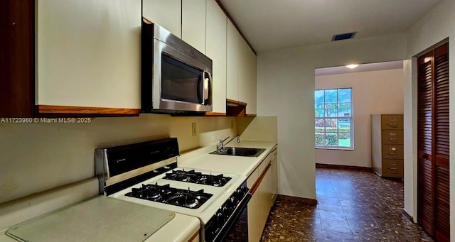 kitchen with sink, range with gas cooktop, and white cabinets