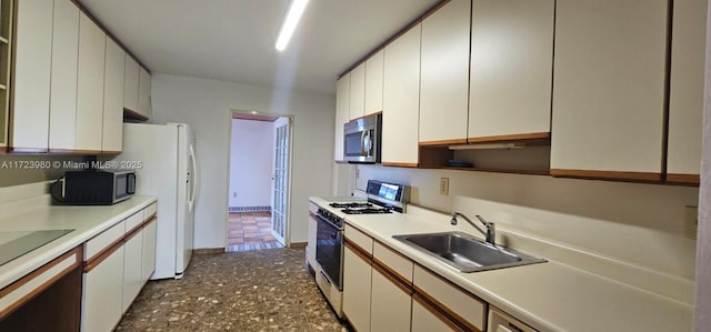 kitchen featuring gas range, sink, white fridge, and white cabinets