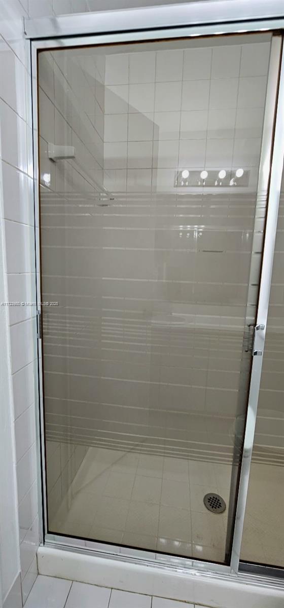 bathroom featuring an enclosed shower, tile patterned floors, and toilet