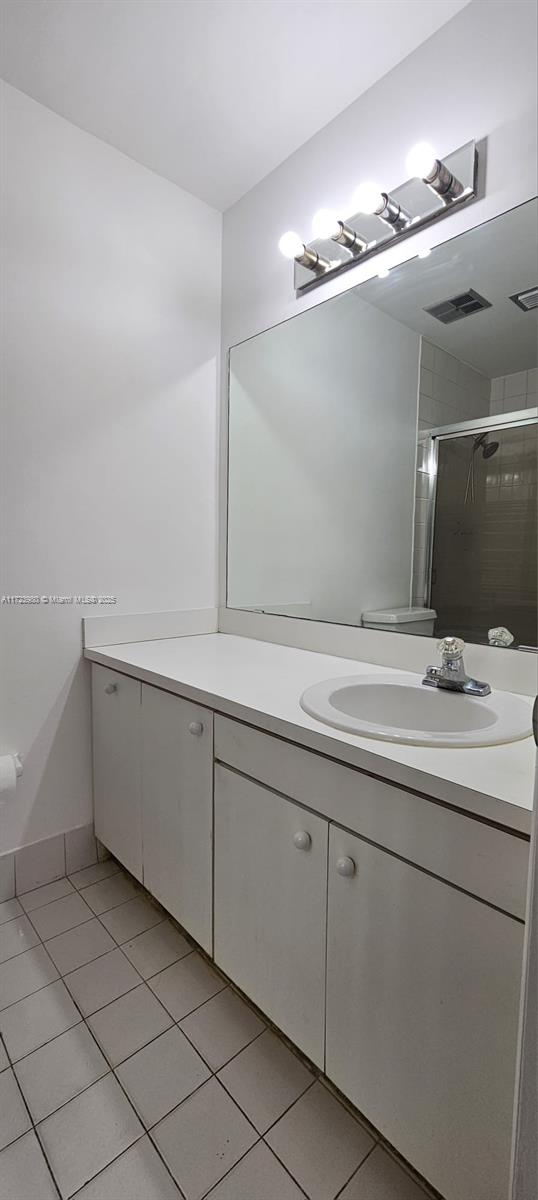 bathroom with tile patterned floors, vanity, toilet, and an enclosed shower