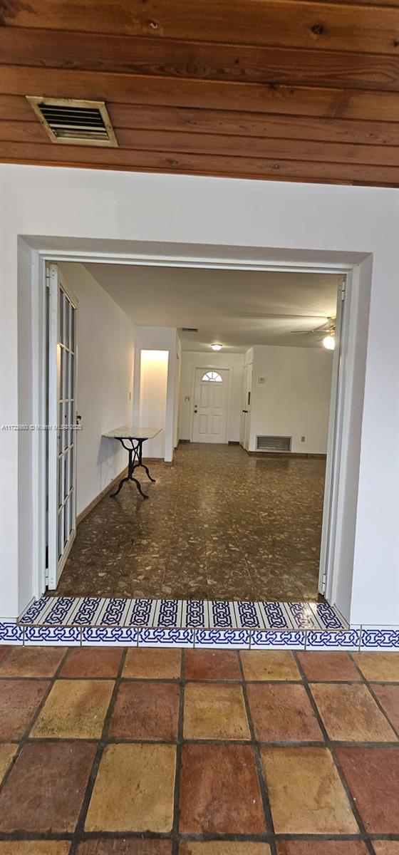 interior space with dark tile patterned flooring, wooden ceiling, and a healthy amount of sunlight