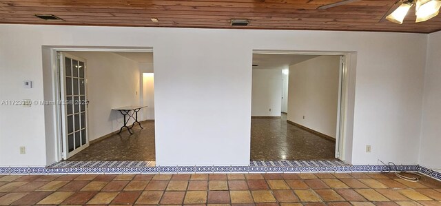 interior space with dark tile patterned floors, a wealth of natural light, and wooden ceiling