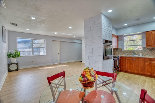 dining room with a healthy amount of sunlight, sink, and light hardwood / wood-style flooring