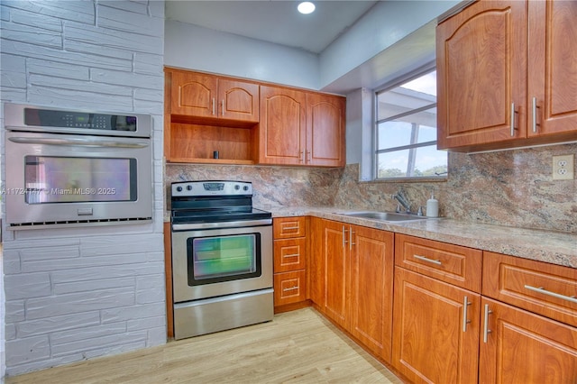 kitchen featuring decorative backsplash, sink, stainless steel appliances, and light wood-type flooring