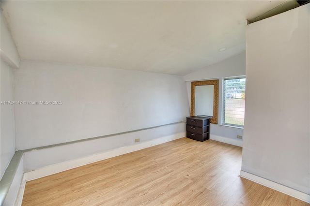 spare room featuring light wood-type flooring and lofted ceiling