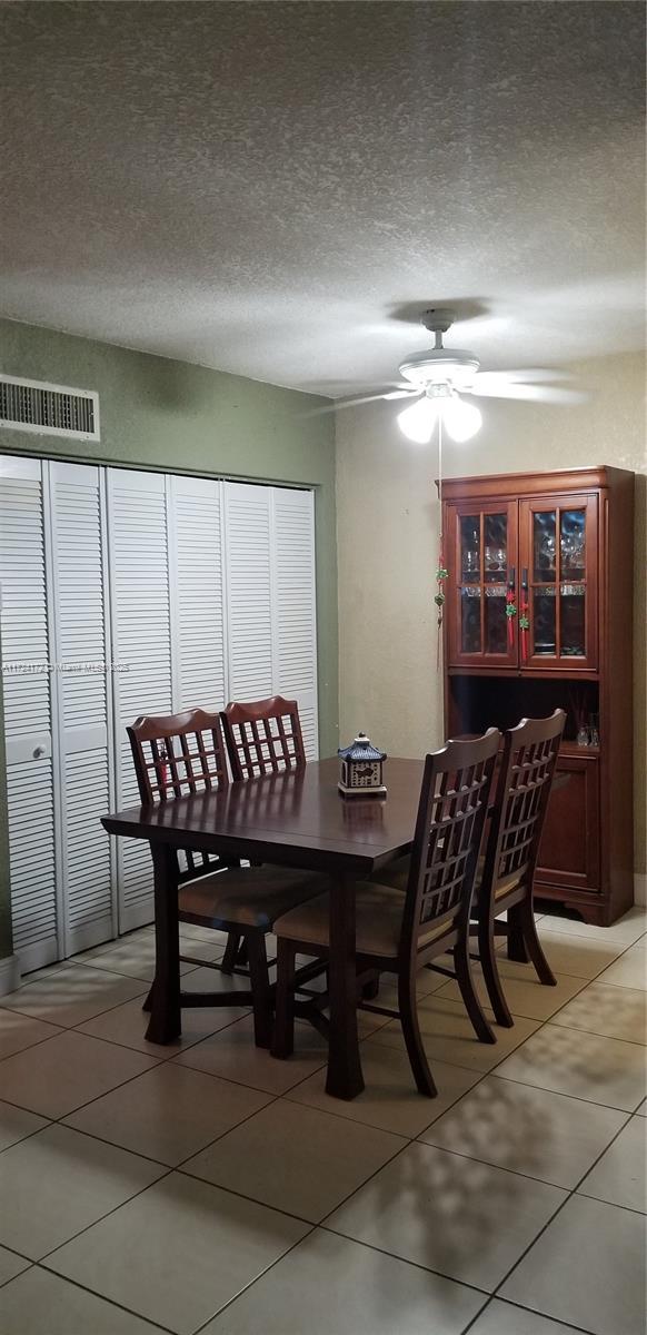 dining area featuring ceiling fan, tile patterned floors, and a textured ceiling